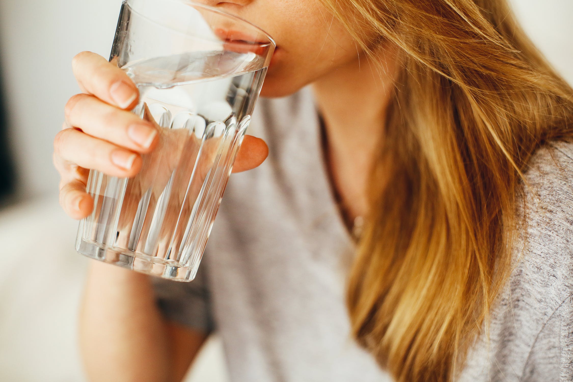 woman drinking a full glass of water to stay hydrated and safe for summer