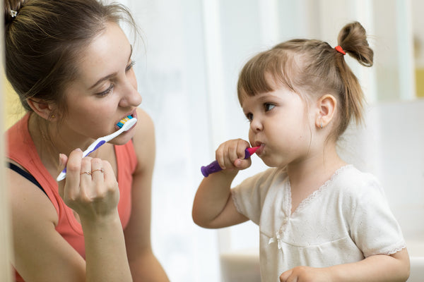 woman and girl brushing teeth