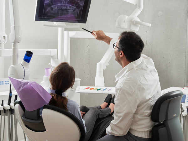 dentist looking at teeth x-ray with patient 