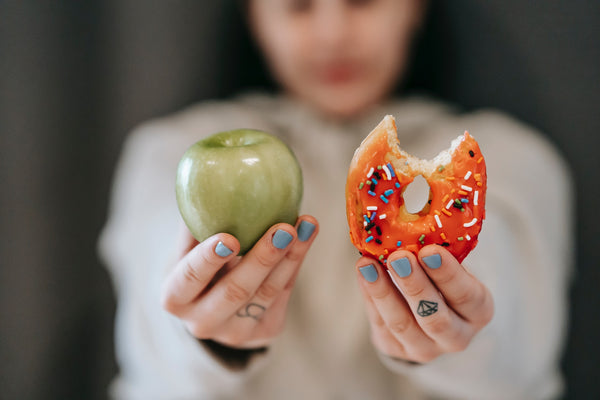 girl making dietary choice between donut and apple