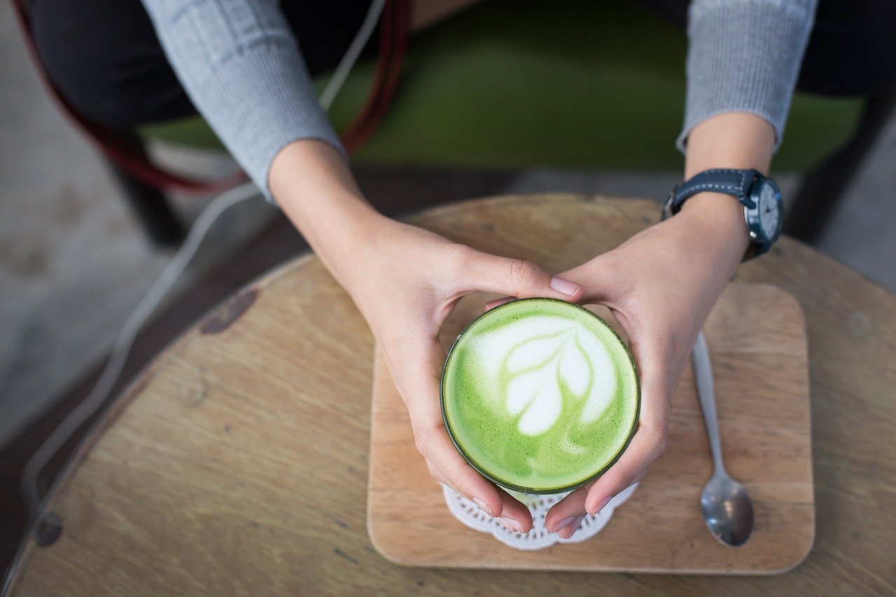 person holding cup of matcha tea