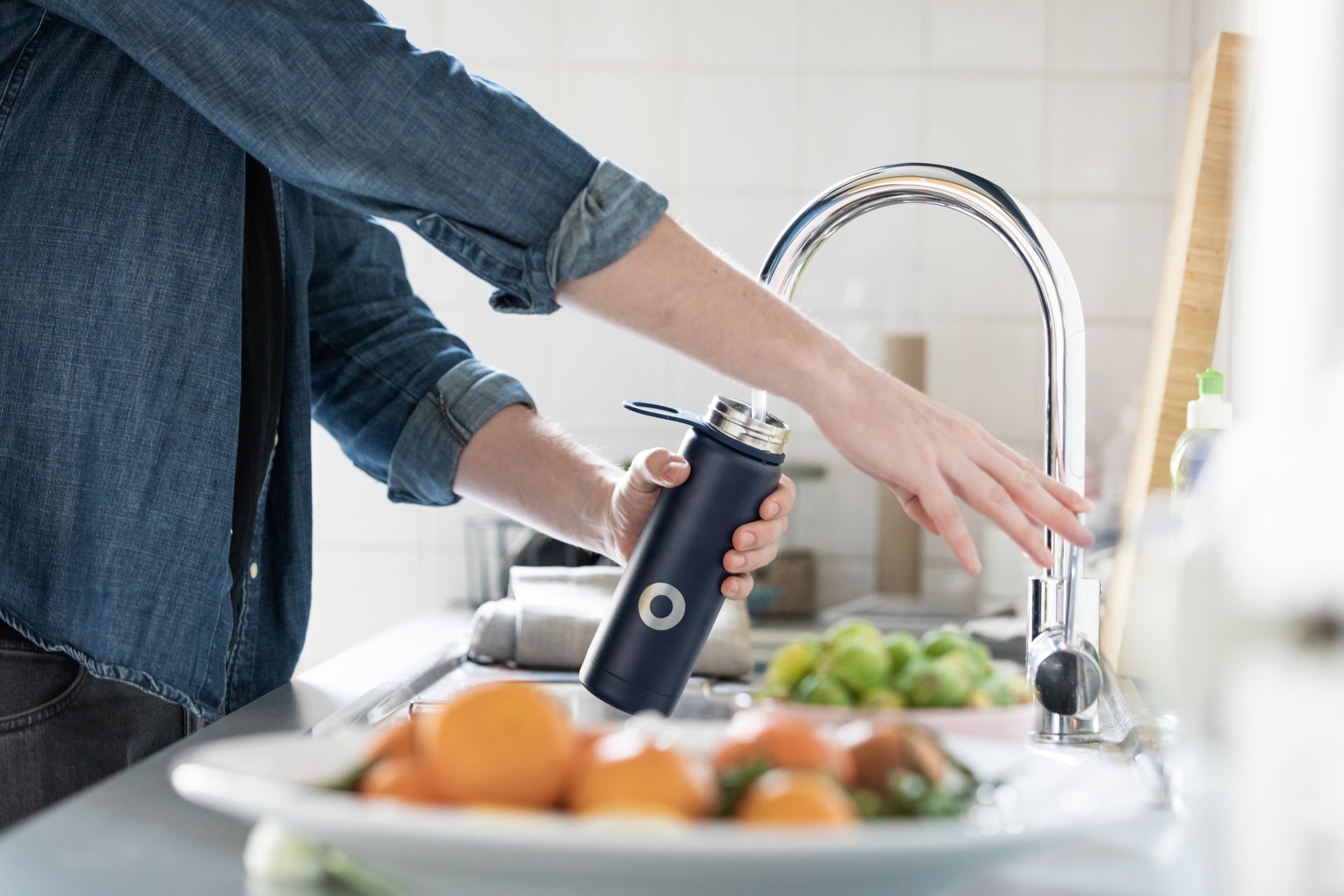 person filling water bottle to keep physically and mentally healthy