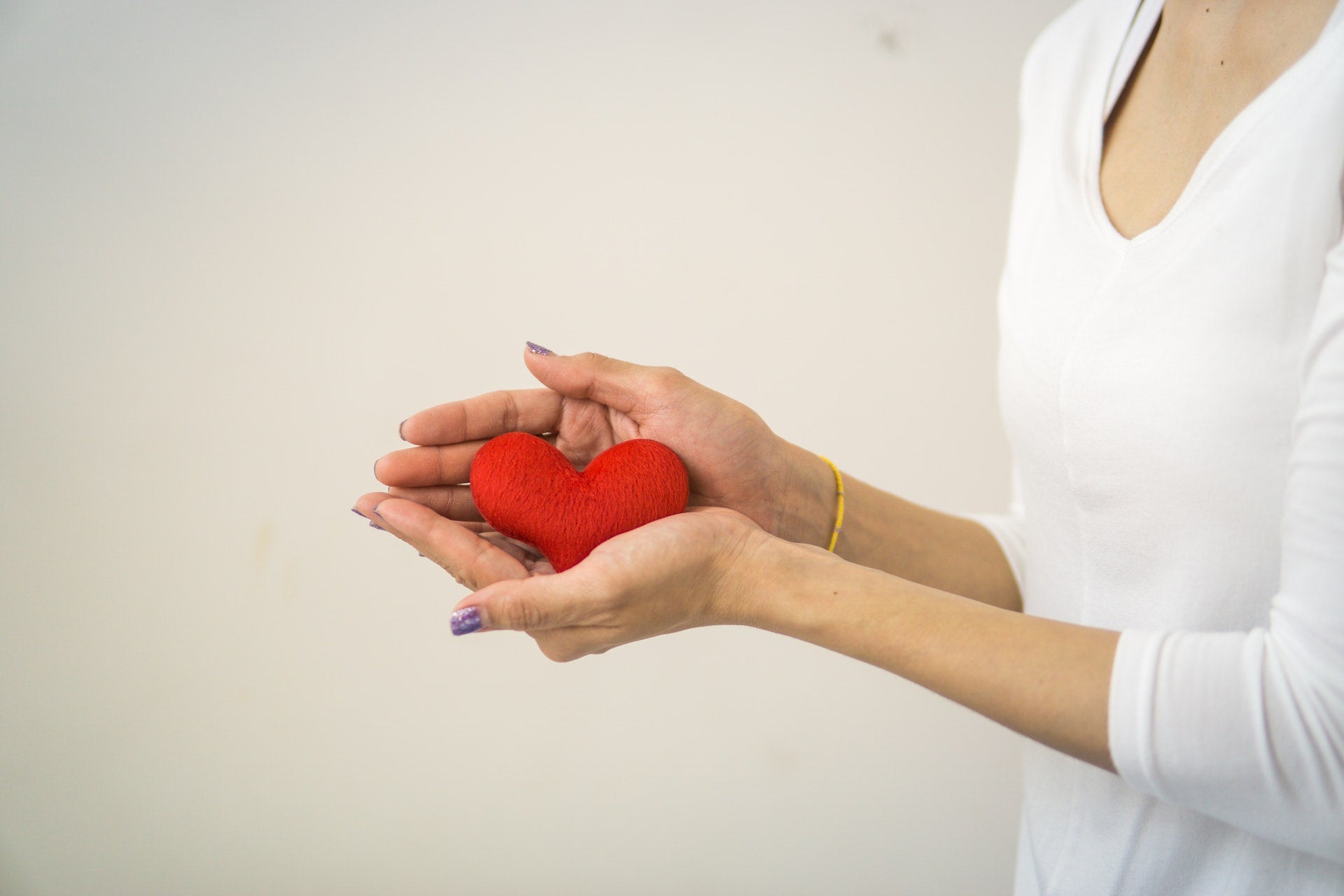 woman holding model heart as reminder to reduce plaque from arteries