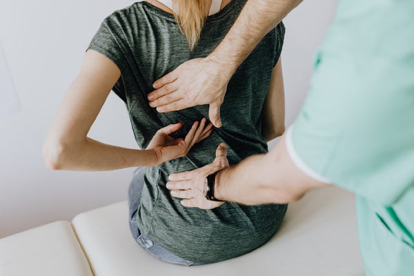 doctor checking woman's back pain