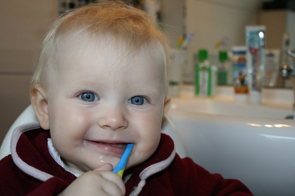 a smiling baby brushing teeth to keep it healthy