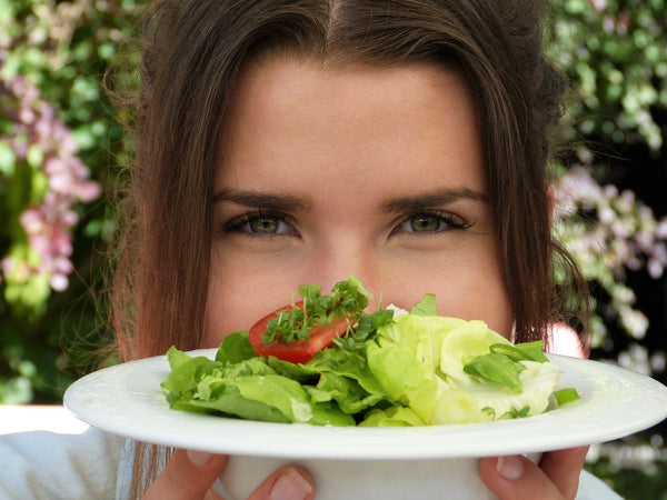 a woman showing a close-up plate of fresh vegetables for a healthy diet