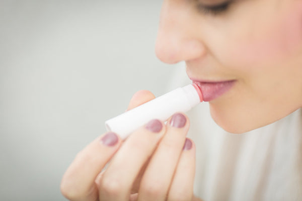 woman applying lip balm to protect skin