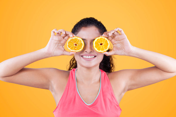a girl holding two fresh orange cuts for healthier skin