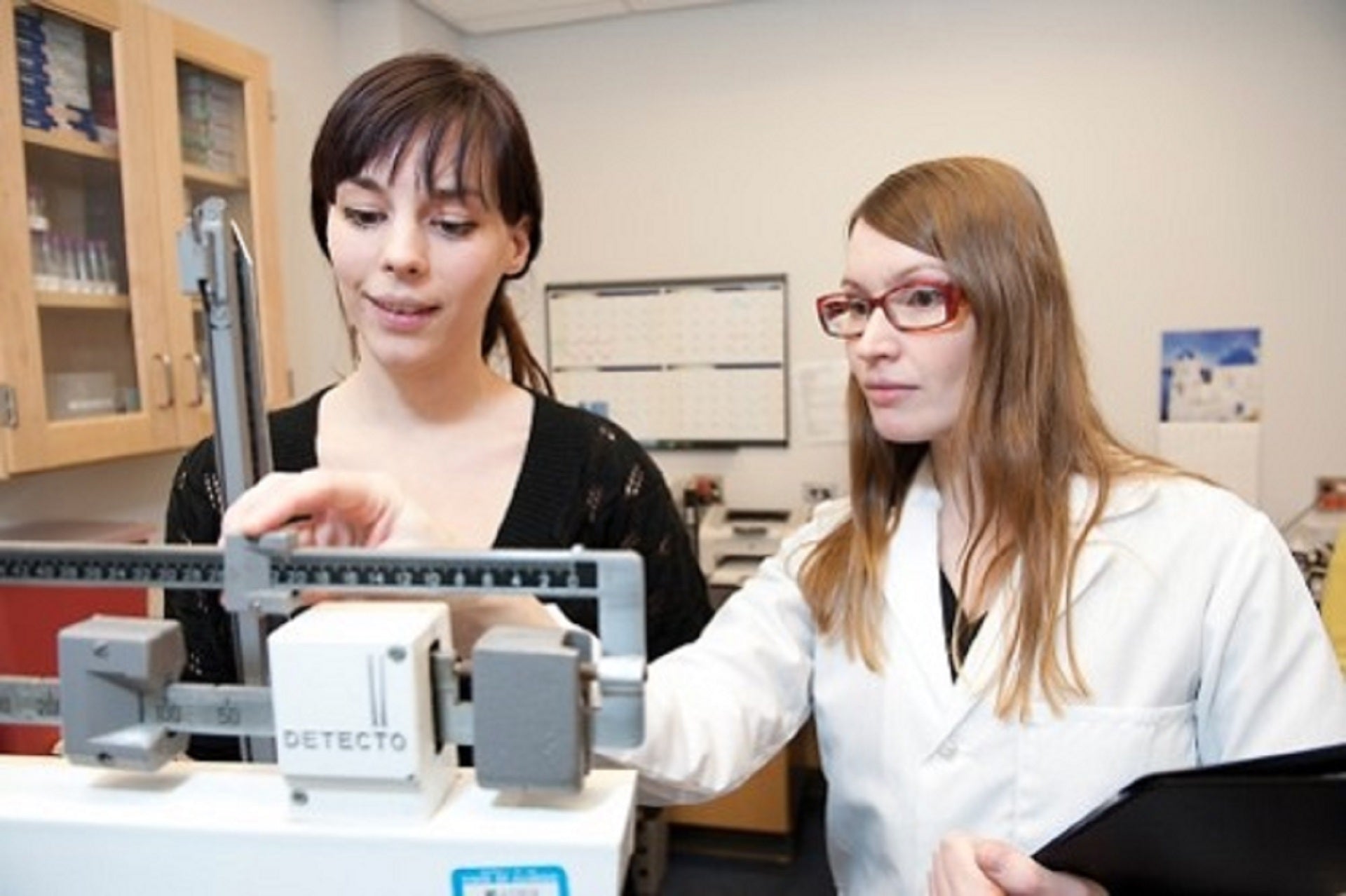 woman and dietician checking scale for weight loss
