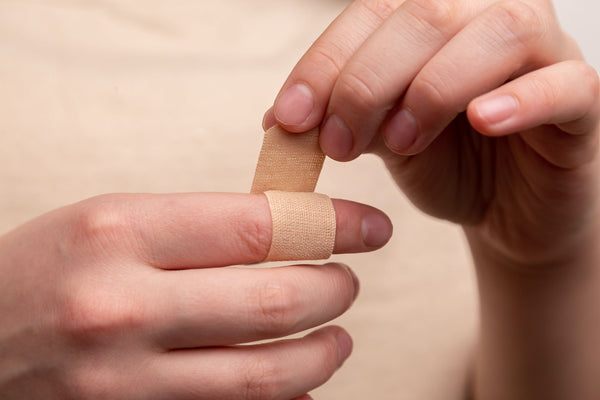 woman putting Bandaid on finger wound