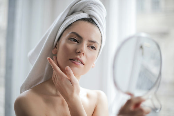 woman looking at her skin in mirror